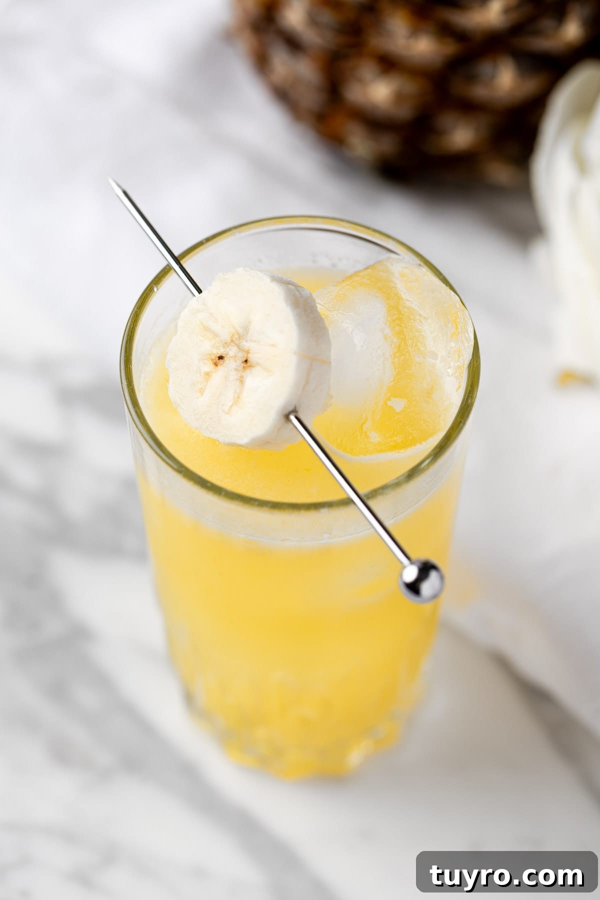Creamy Banana Rum Cocktail Recipe 7 A banana rum punch cocktail on a white marble table.
