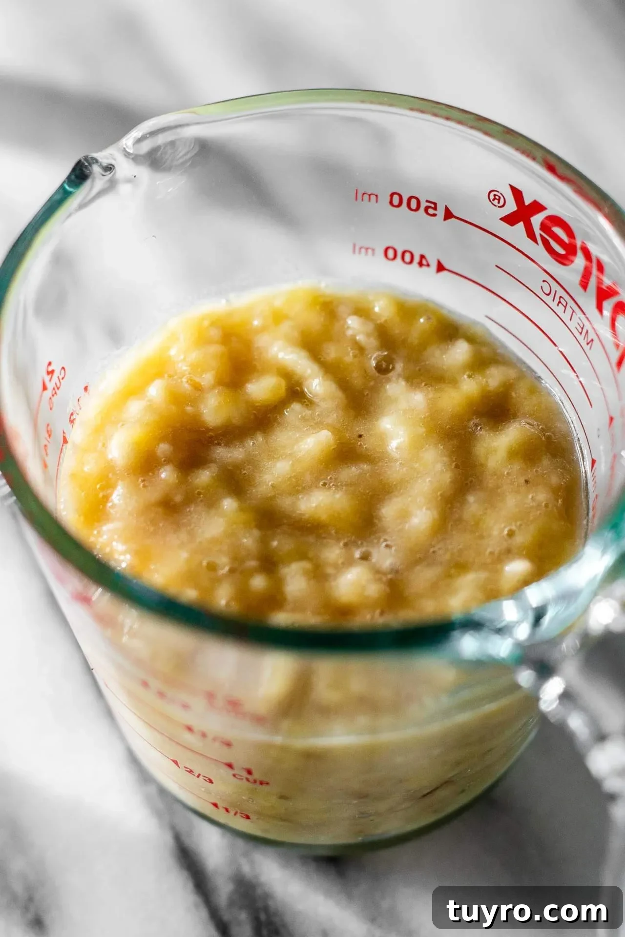 mashed bananas for banana muffin in measuring cup