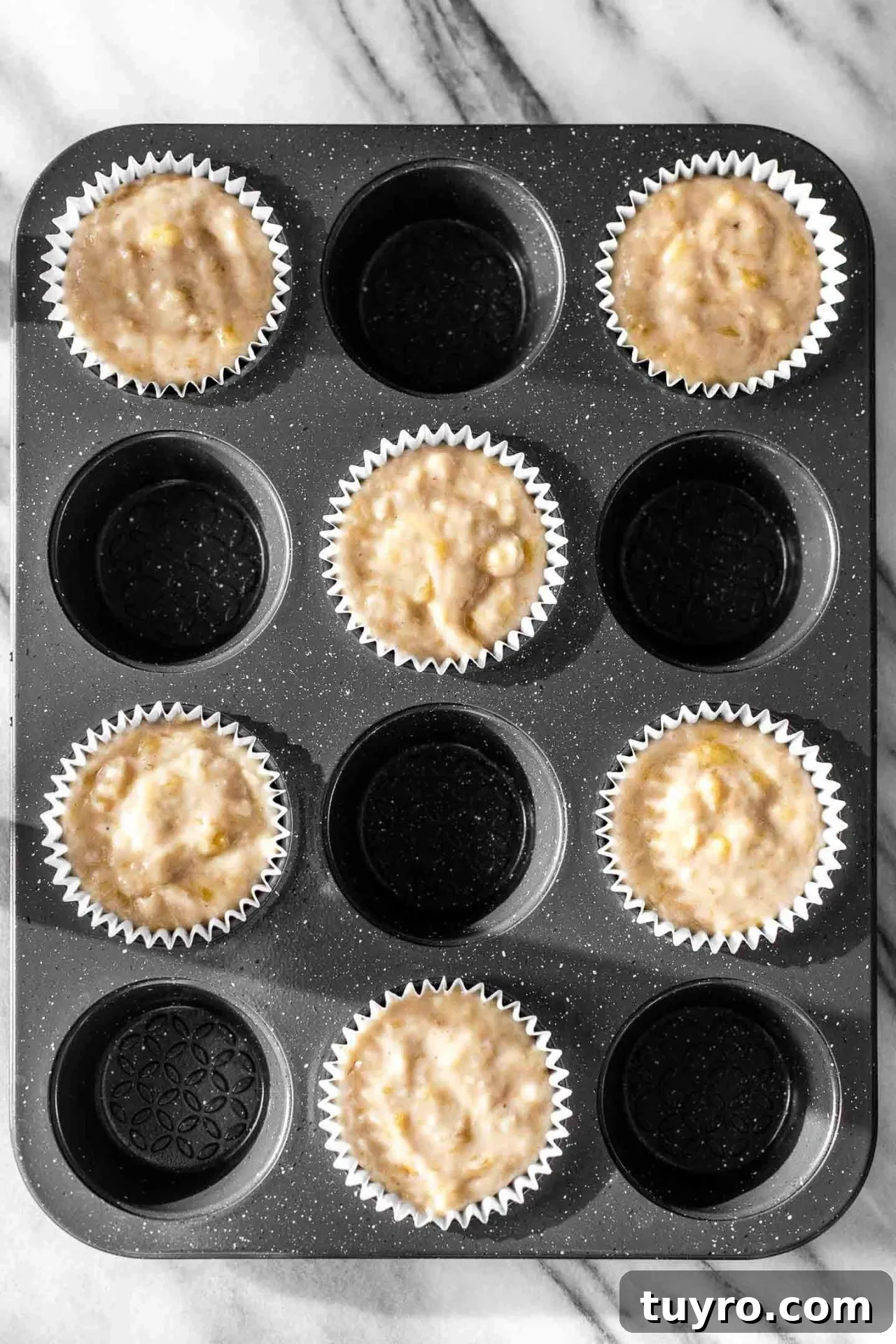 banana muffin batter divided into muffin cups in tin