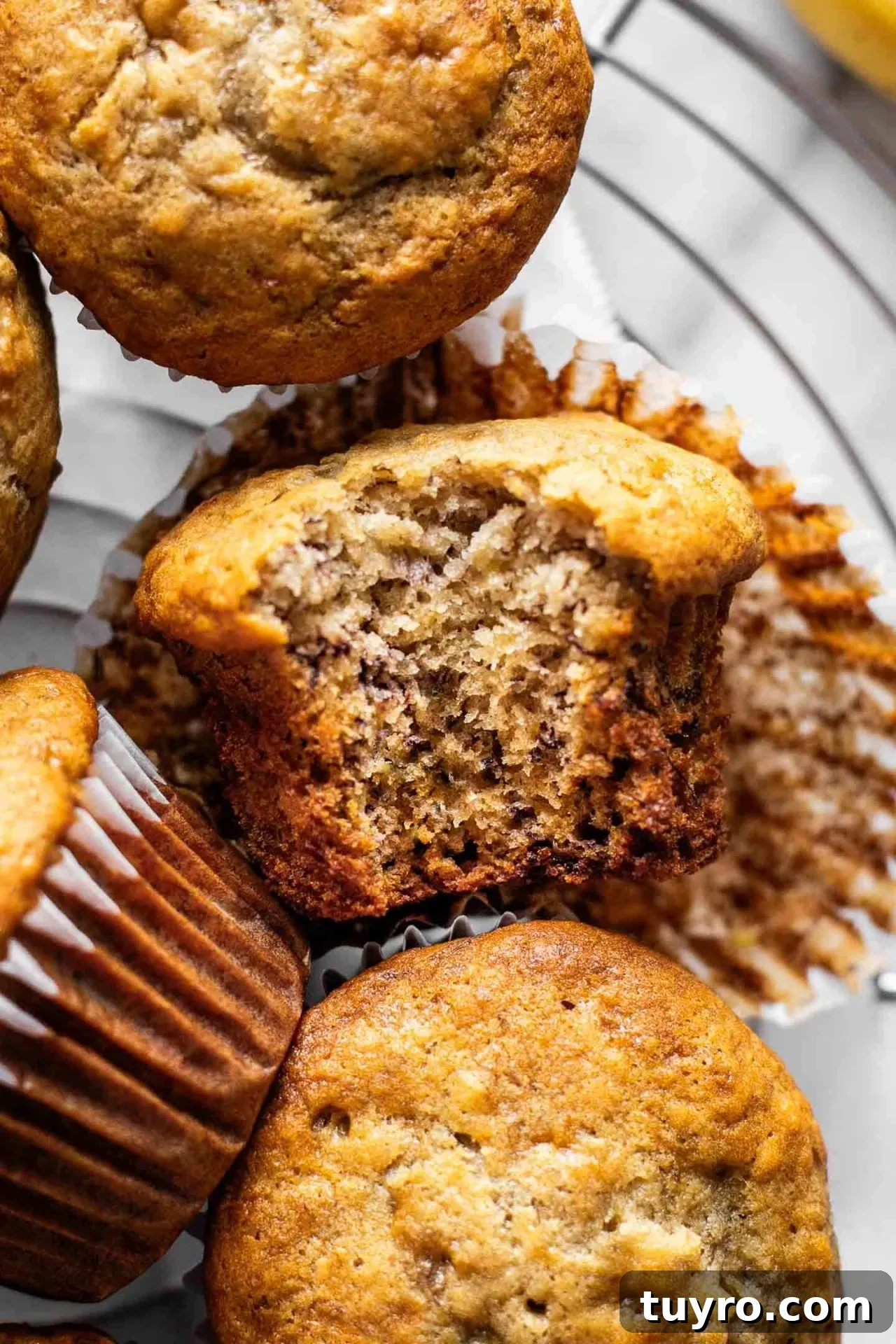 banana muffins on wire rack with bite missing from 1 muffin