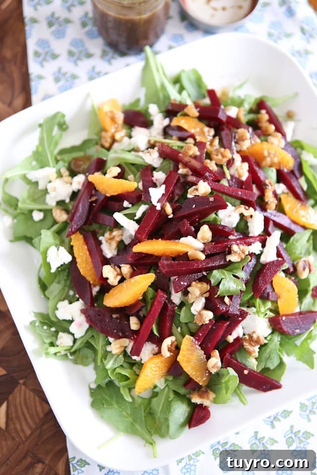 Spring Beet and Goat Cheese Salad with Walnuts plate of arugula salad topped with goat cheese, beet strips, orange slices, and walnuts