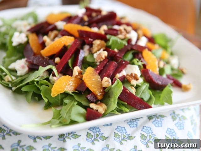 Spring Beet and Goat Cheese Salad with Walnuts plate of arugula salad topped with goat cheese, beet strips, orange slices, and walnuts