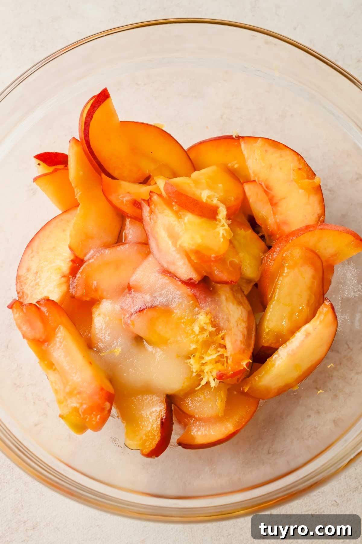 Rustic Peach and Berry Galette Recipe 4 sliced peaches, sugar, lemon zest and extract in a glass mixing bowl.