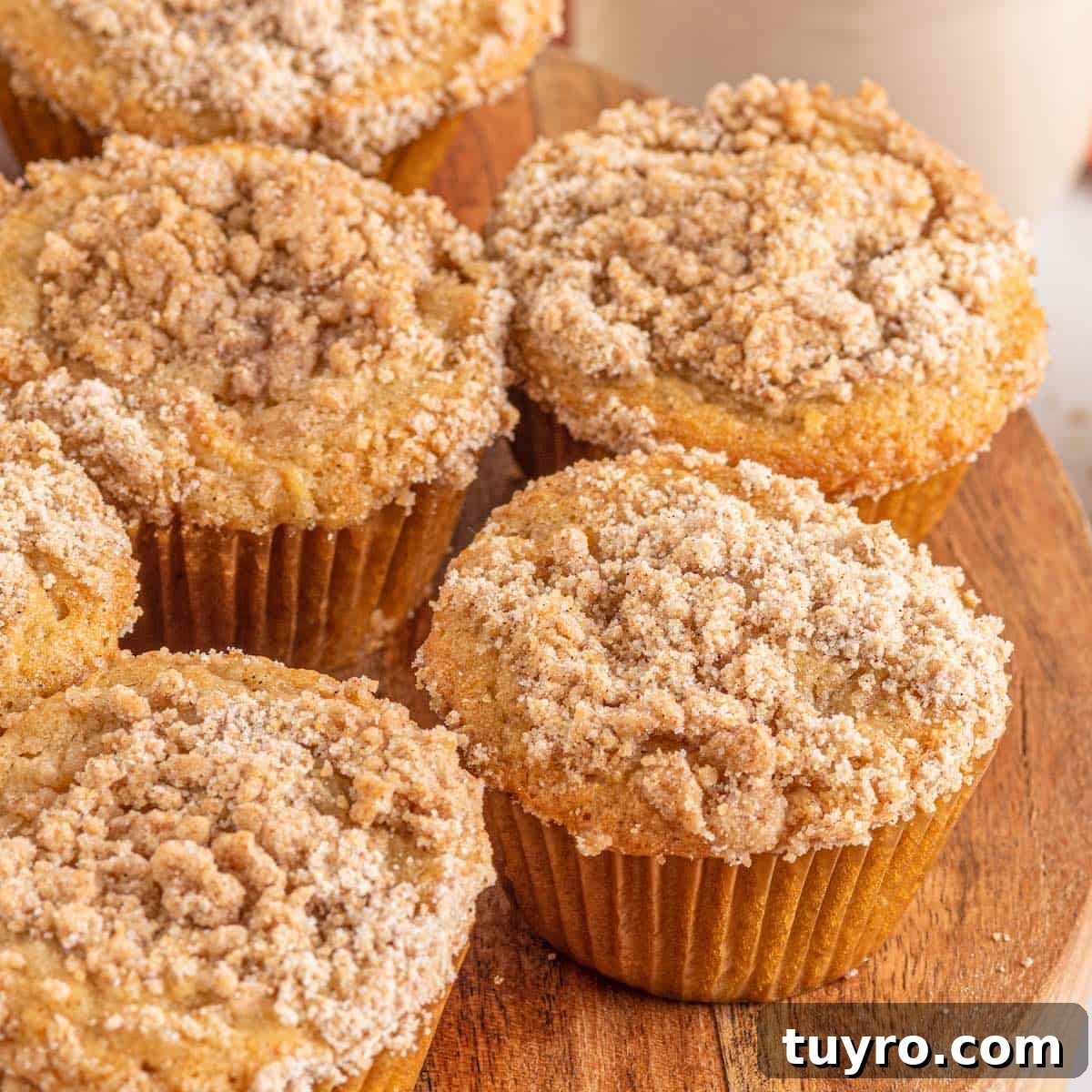 Crumb topped apple muffins on a wood platter.